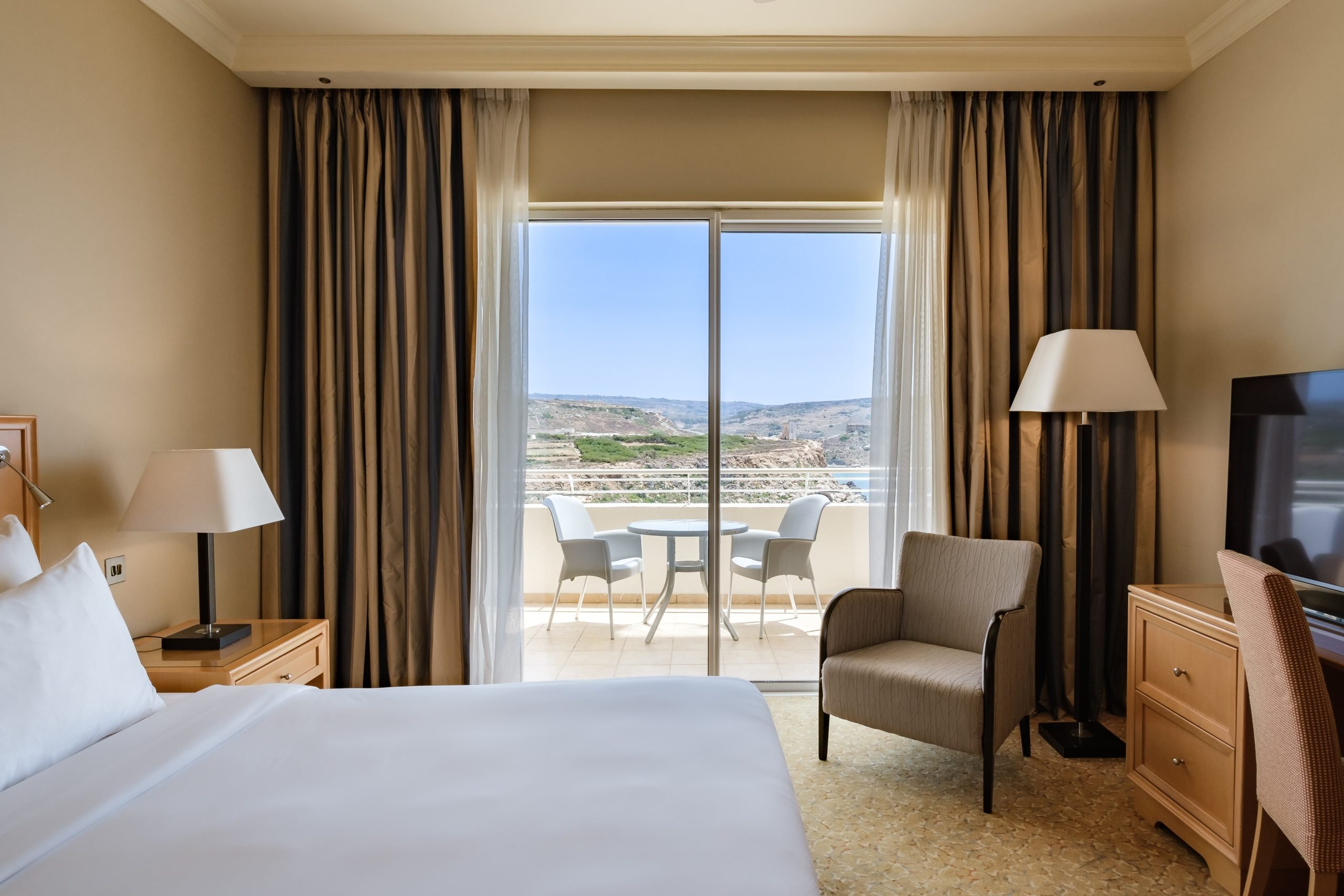 Chambre du Radisson Blu Golden Sands à Malte, lit double et balcon ouvert vers la mer.