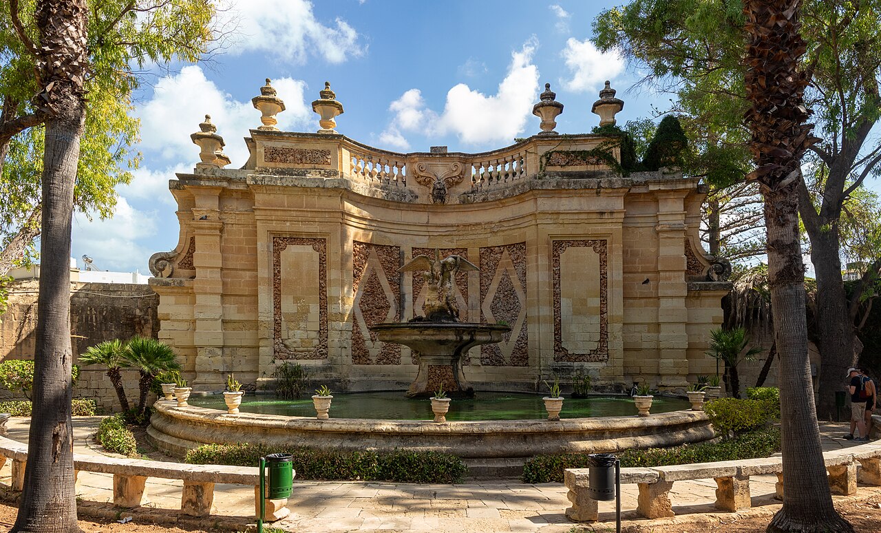 Une fontaine et son décor de pierre parmi les arbres des jardins de San Anton, à Malte.