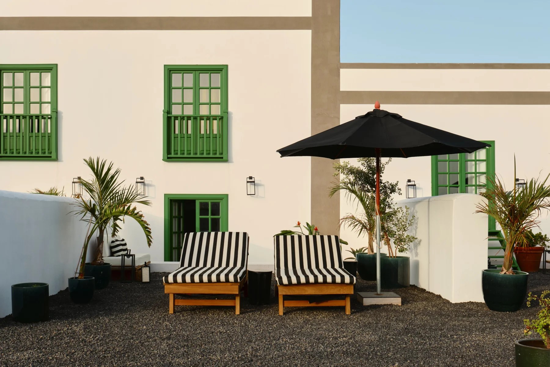 Transats rayés au pied des fenêtres vertes de la maison du César Lanzarote.