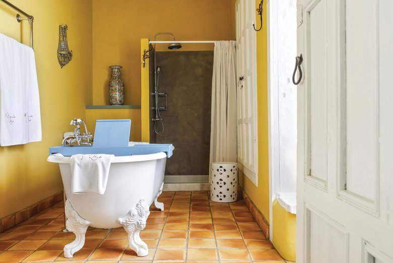 Salle de bains de l'Hacienda de Abajo avec baignoire sur pieds et murs jaunes.