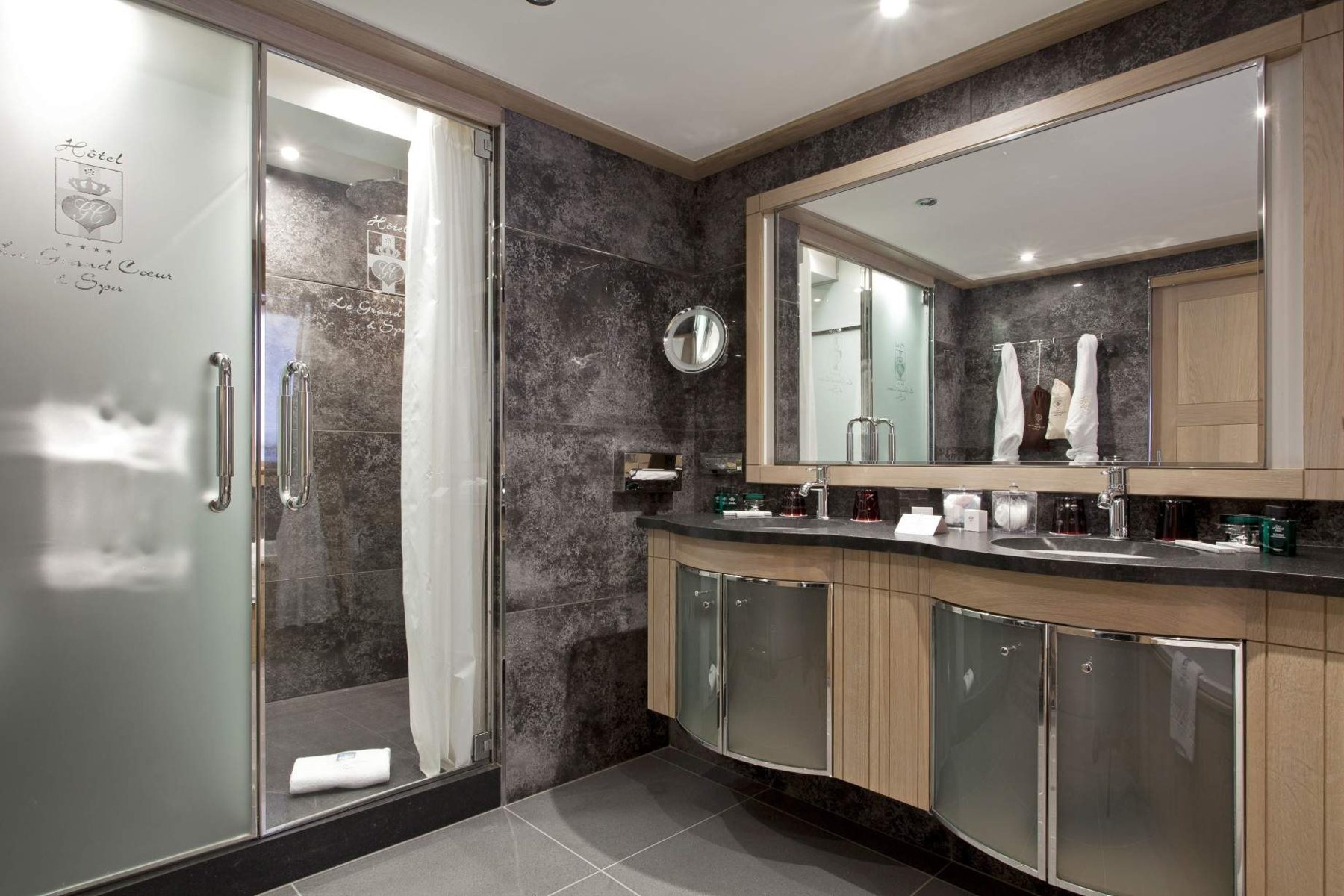Une salle de bains en pierre avec double vasque : Le Grand Cœur & Spa à Méribel.