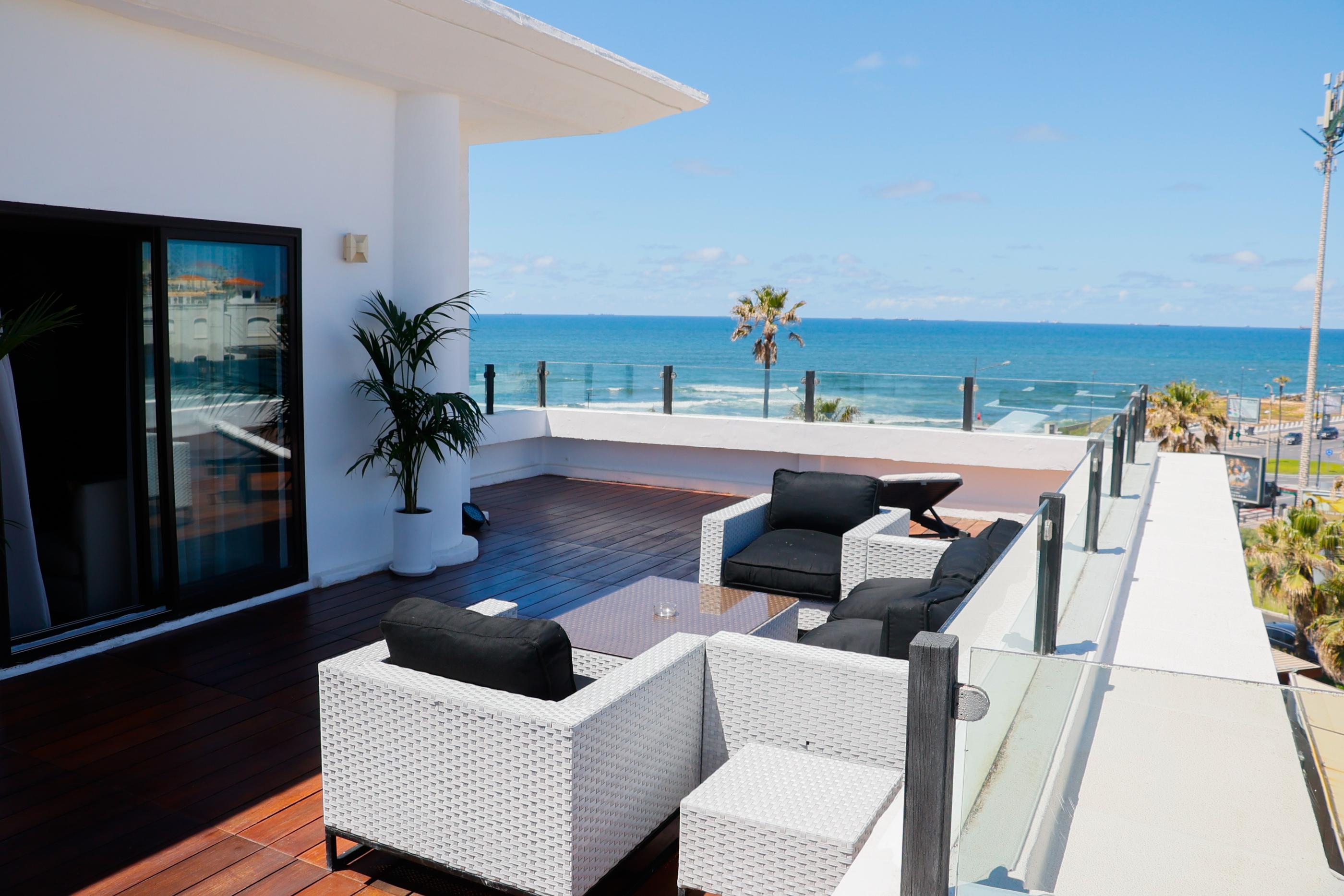 Terrasse meublée face à l'Atlantique et balustrade vitrée de Villa Blanca Urban Hotel, sur la Corniche de Casablanca.