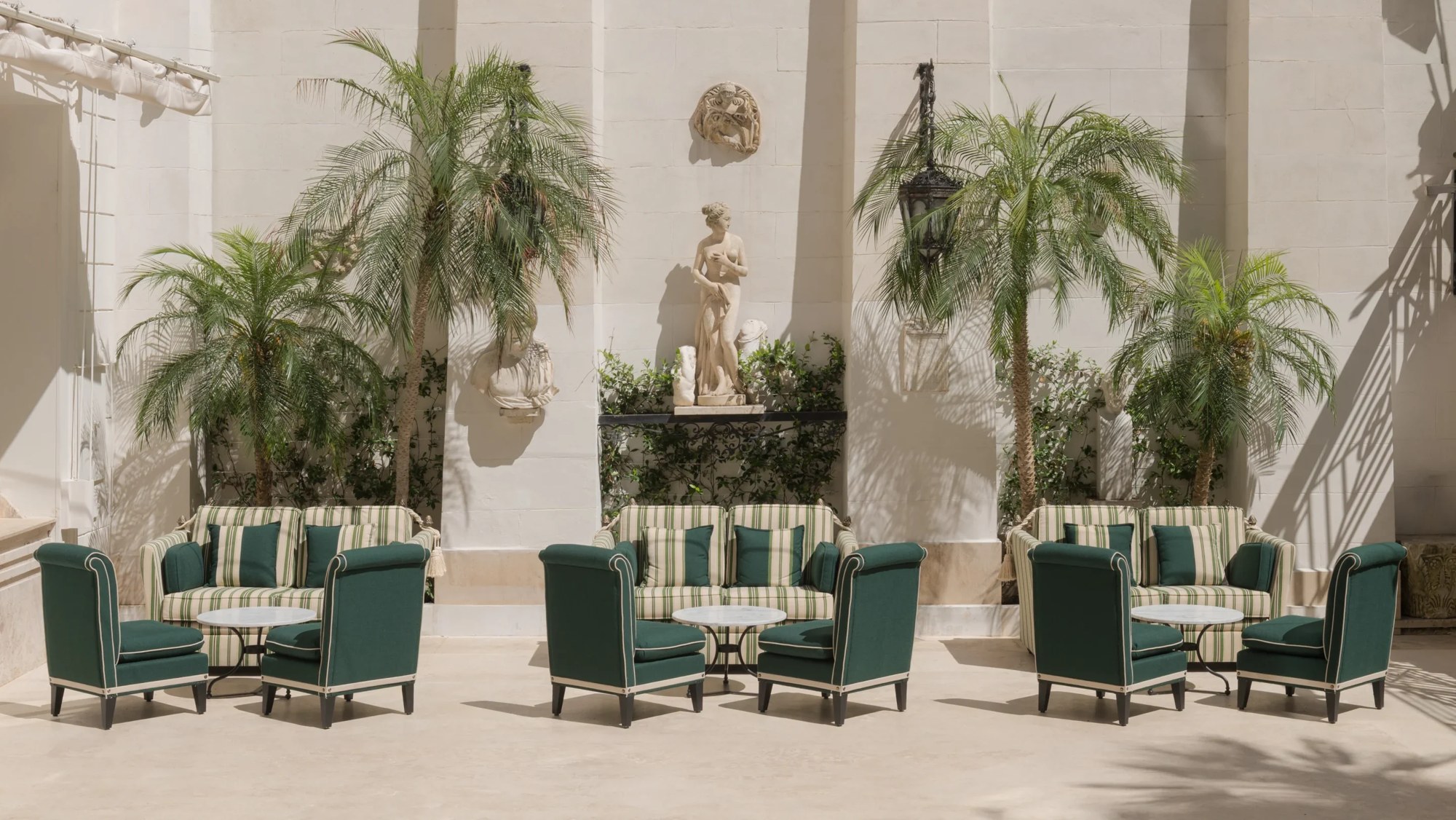 Palm Court du Hassler Roma à Rome, fauteuils verts et palmiers dans la cour.