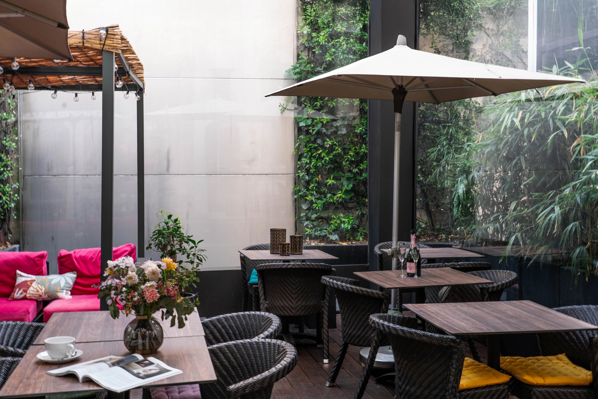 Le patio de l'Eastwest avec tables, végétation et parasol - Eastwest Hotel, Genève.