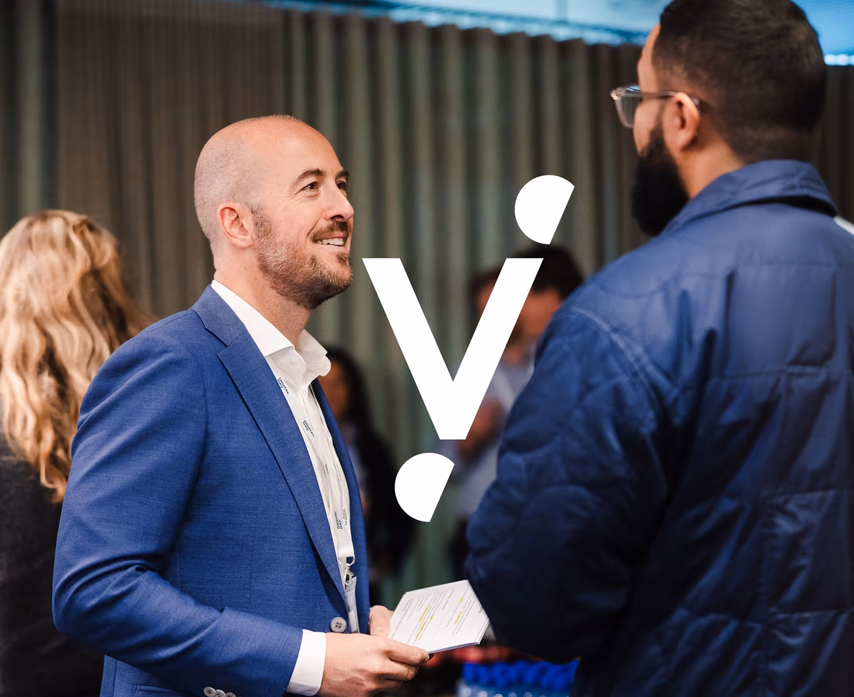 blue2purple - Two men in conversation at a company event, with a white logo overlay