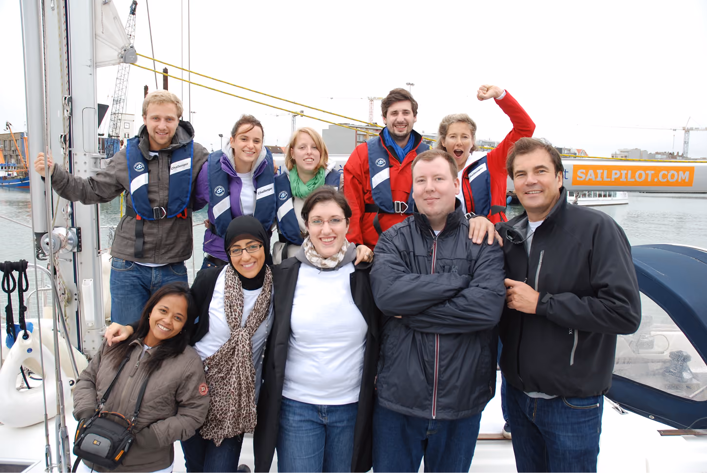 blue2purple - Team in sailing jackets posing on a boat at the harbour