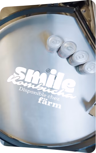 blue2purple - Smile Kombucha cans moving through a production line with the caption Disponible chez farm