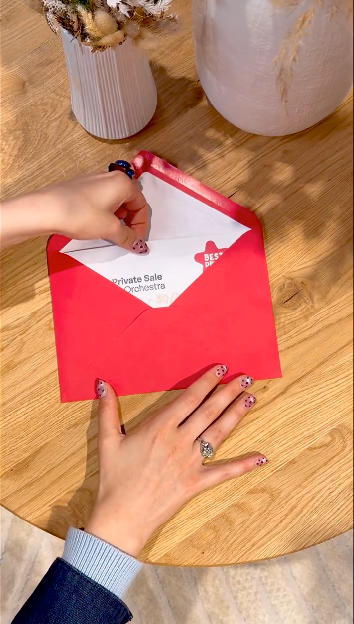 blue2purple - A person opening a red Orchestra Private Sale envelope on a wooden table