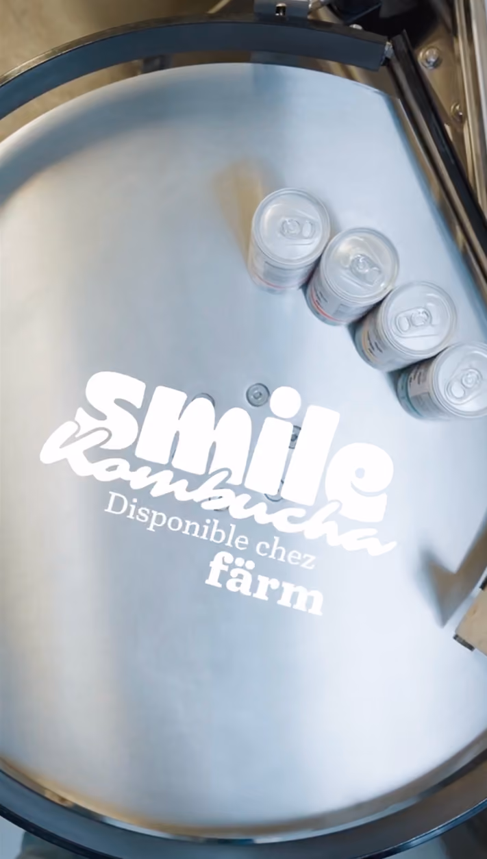 blue2purple - Smile Kombucha cans moving through a production line with the caption Disponible chez farm