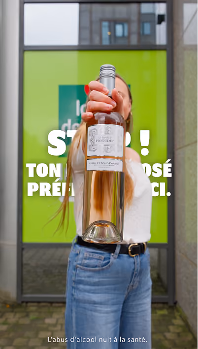 blue2purple - A woman holding a bottle of rose wine in front of a green Louis Delhaize poster