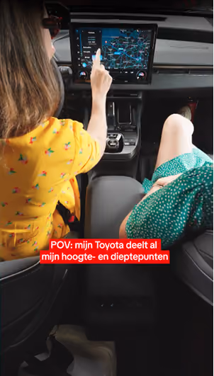 blue2purple - A woman in the passenger seat of a Toyota using the dashboard touchscreen, with Dutch caption