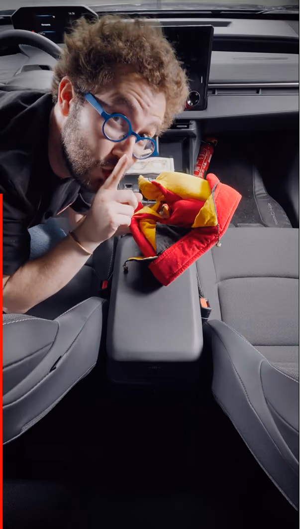 blue2purple - A man leaning into a car cabin holding a snack, making a quiet gesture