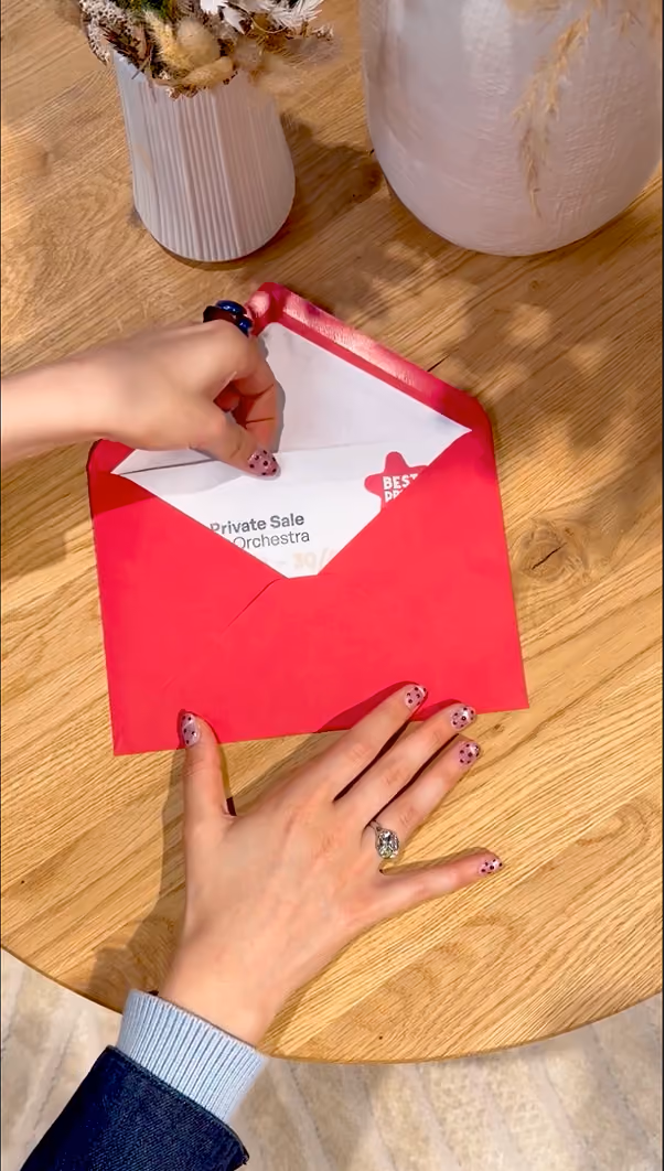 blue2purple - A person opening a red Orchestra Private Sale envelope on a wooden table