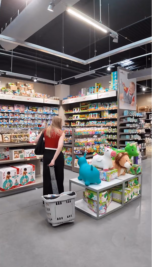 blue2purple - A shopper with a basket browsing shelves of toys in a bright Orchestra store