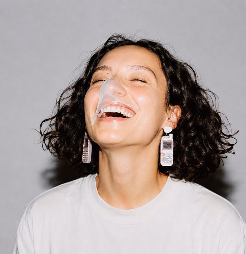 blue2purple - Studio portrait of a woman laughing with burst bubblegum on her face