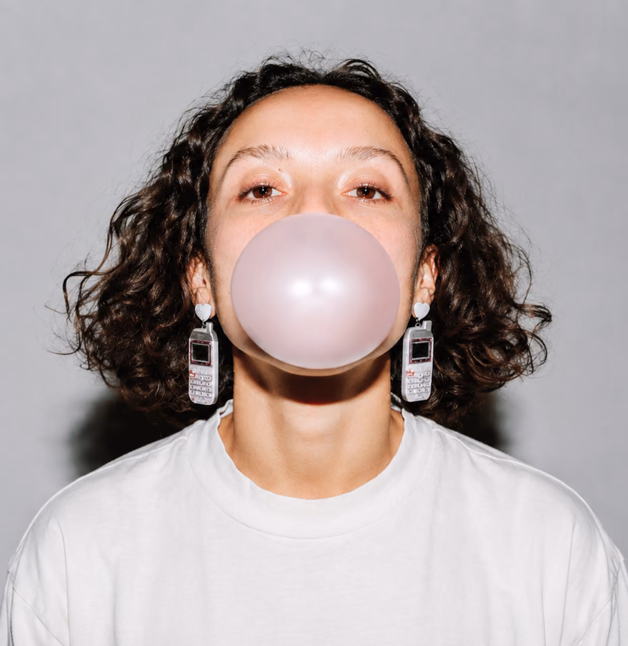 blue2purple - Studio portrait of a woman blowing a large pink bubblegum bubble