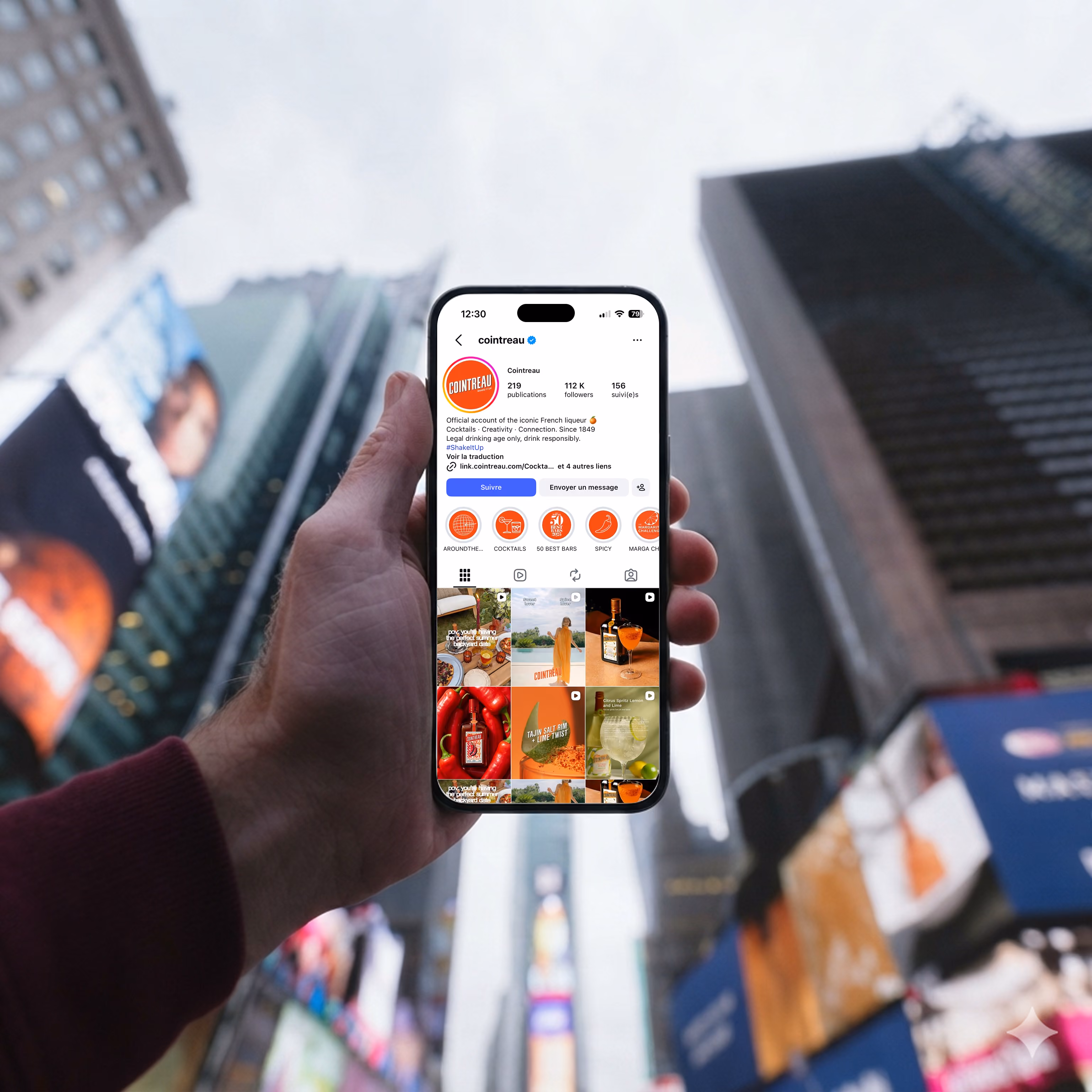 blue2purple - Hand holding a smartphone showing the Cointreau Instagram profile, with city billboards behind