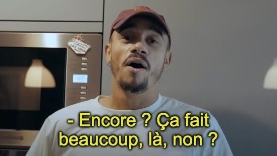blue2purple - Man in a cap speaking to camera in a kitchen with a French subtitle