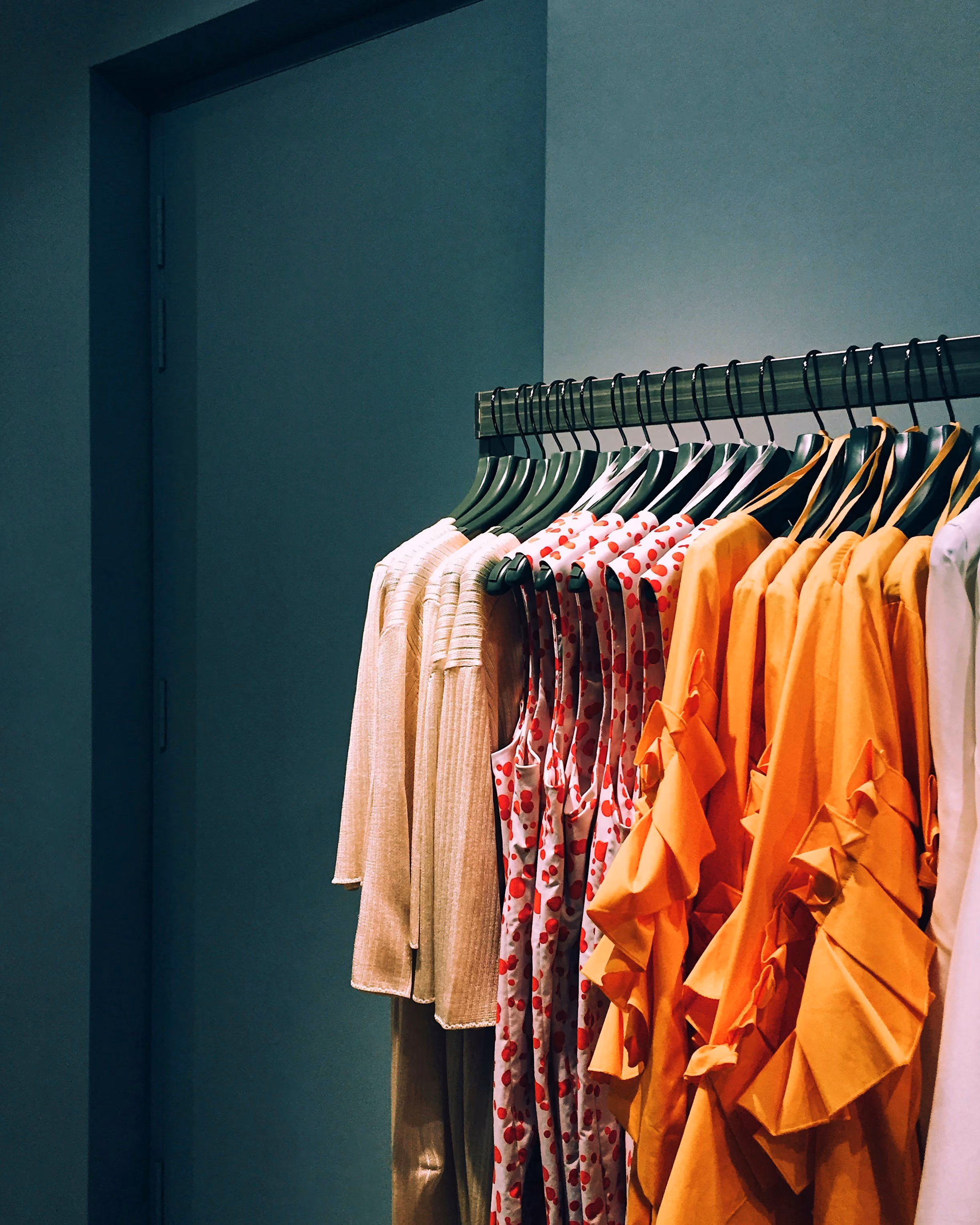 blue2purple - Rail of colourful orange and pink clothing in a dark room