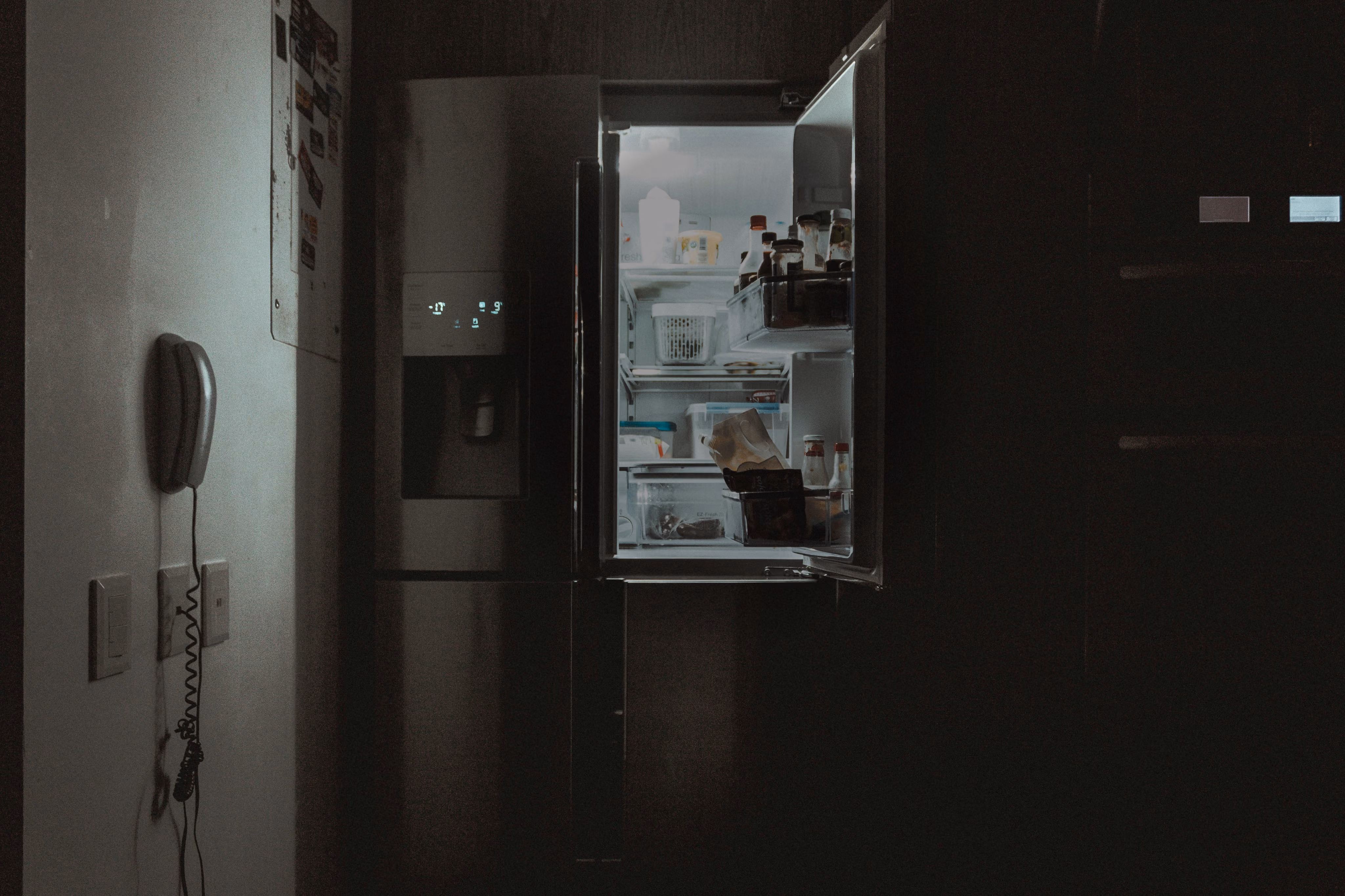 blue2purple - Open fridge in a dark kitchen with a wall phone beside it