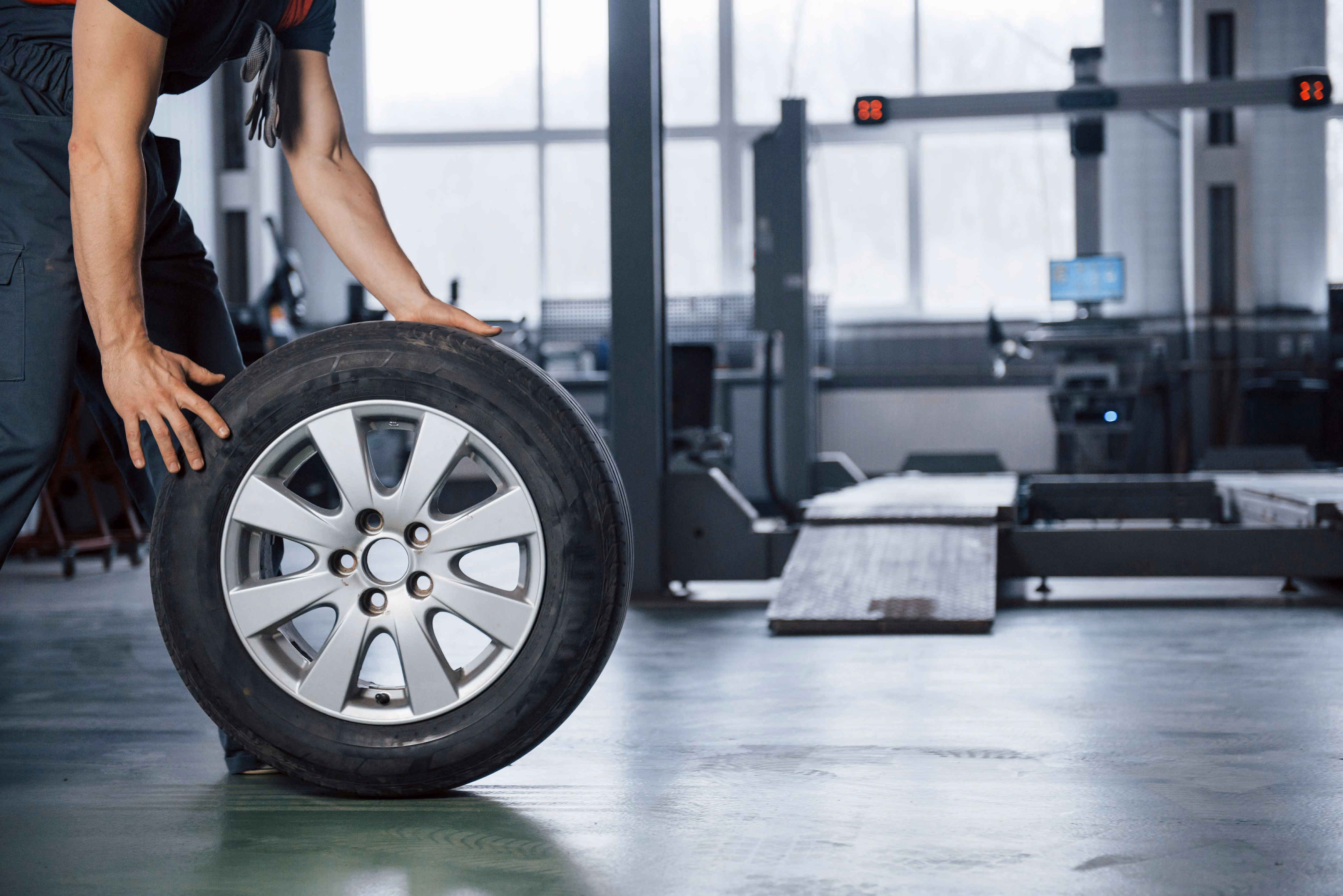 blue2purple - Mechanic holding a car wheel in a repair workshop