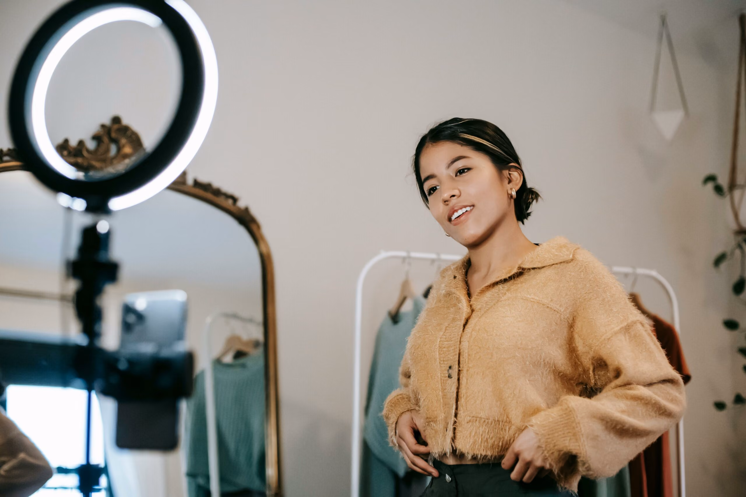 blue2purple - Young woman recording content with a ring light in a clothing studio