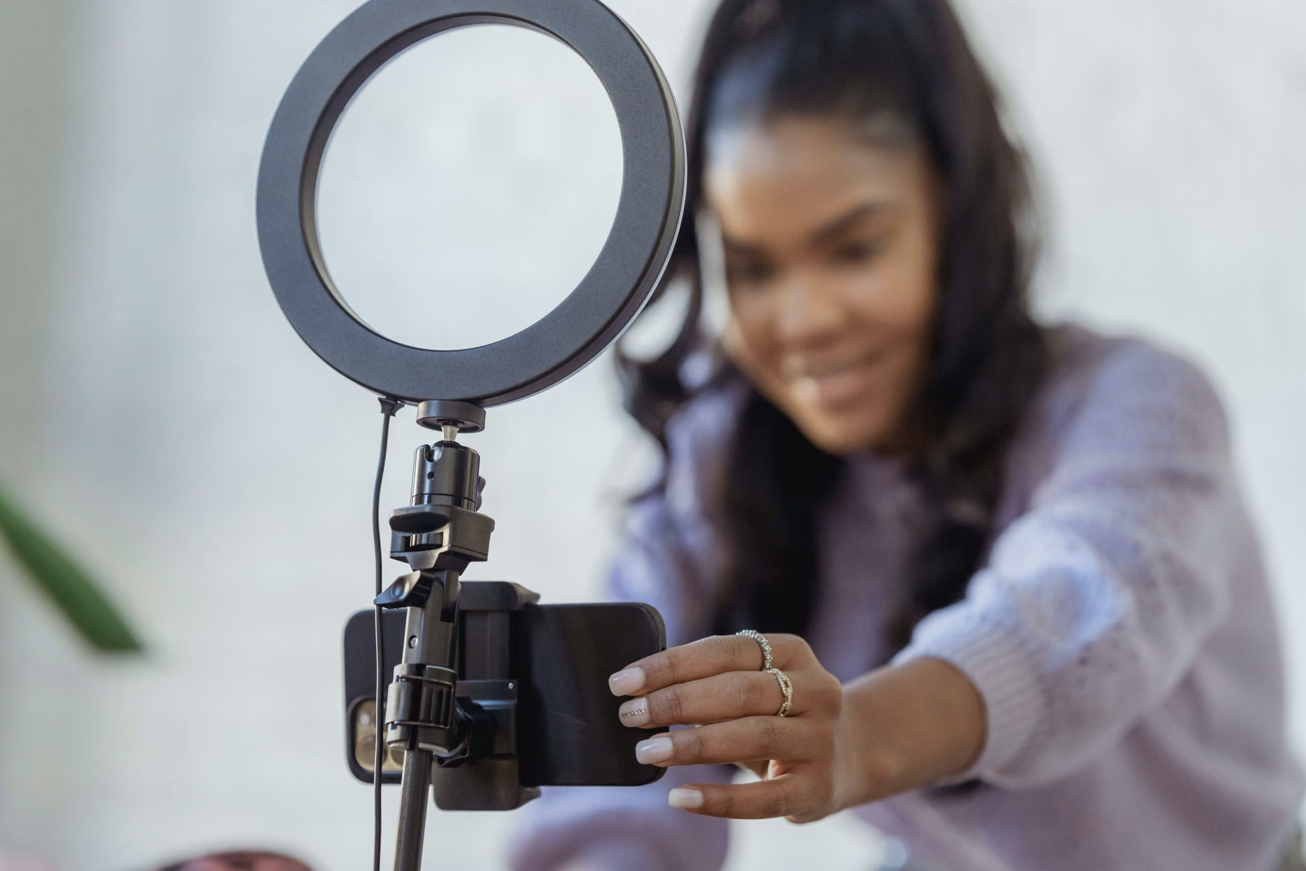 blue2purple - Woman setting up a smartphone on a ring light to record content