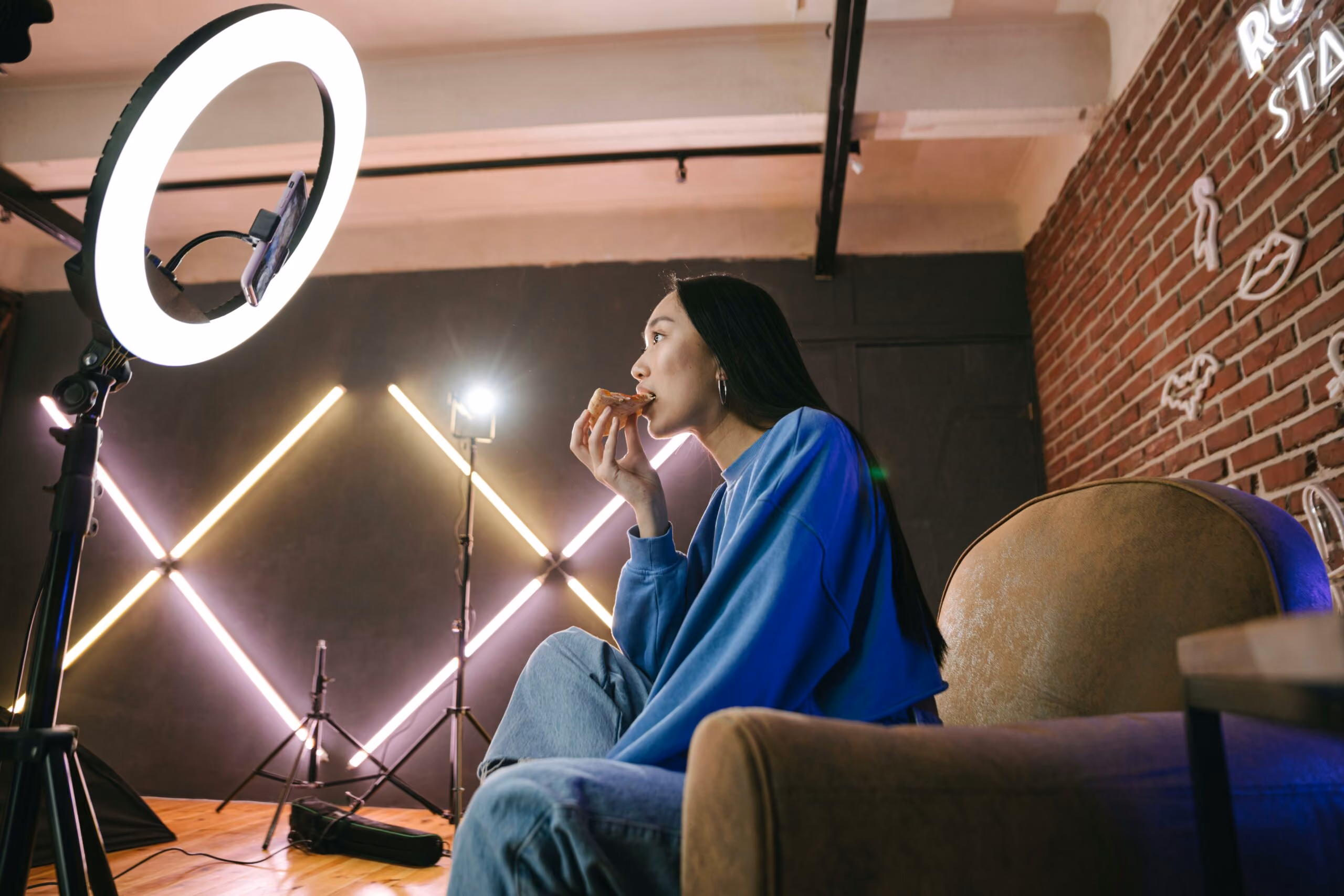 blue2purple - Woman filming content in a studio with a ring light and neon light tubes