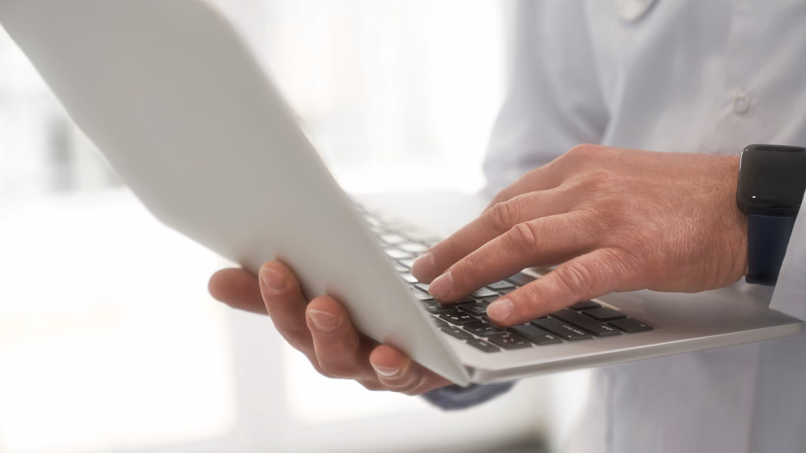 Healthcare provider gently holding an older patient's hands in a supportive gesture.