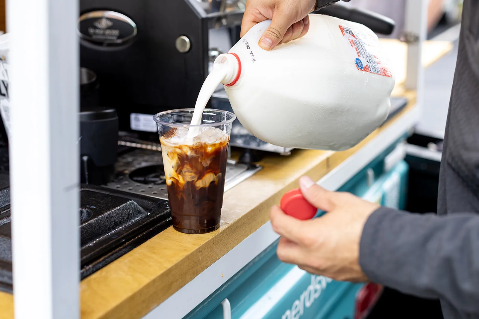 Barista pouring milk into an iced espresso drink