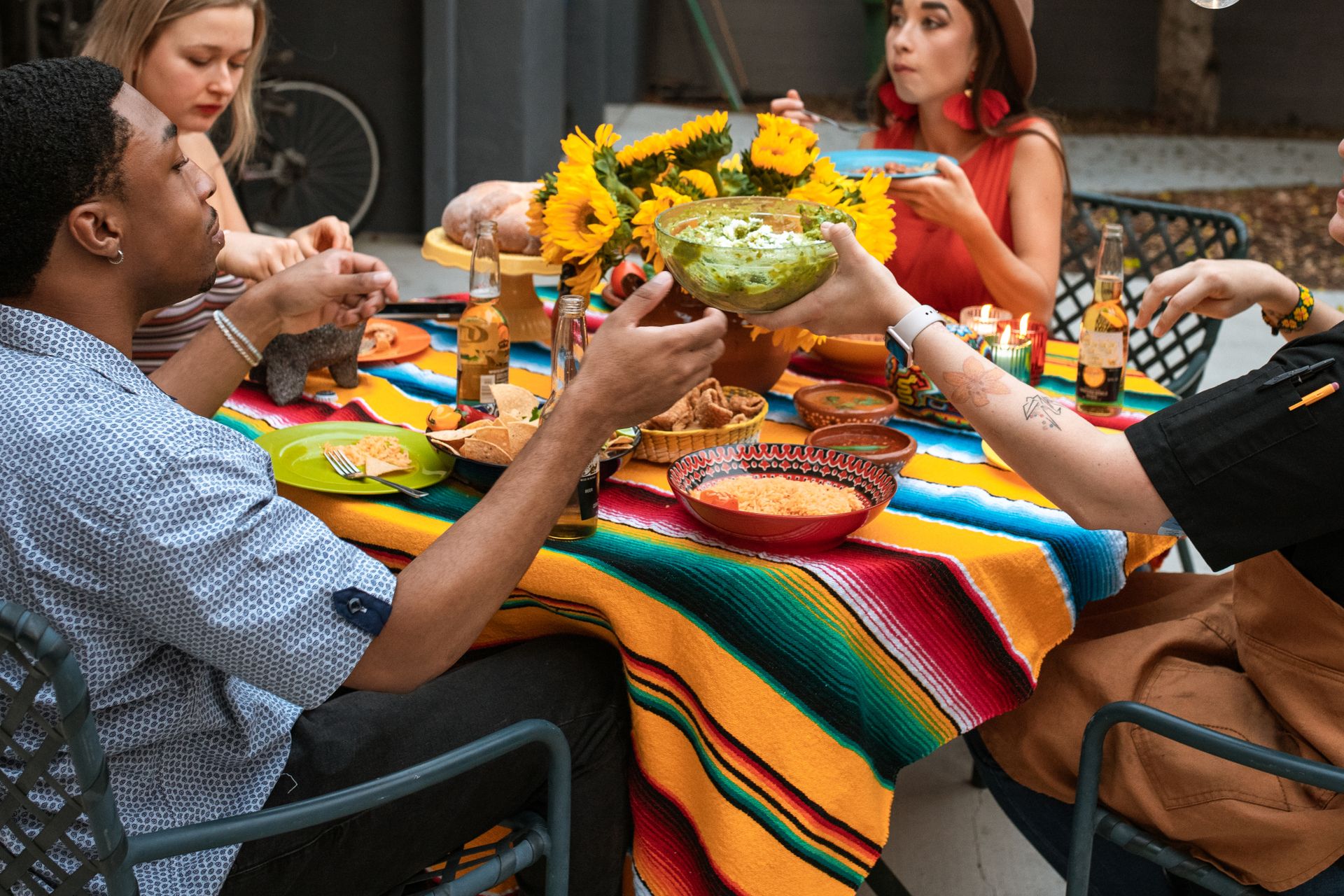 Friends passing a bowl of guacamole across a restaurant table