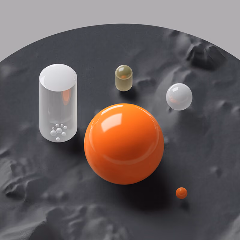 Five shiny spheres of different sizes and colors on a textured dark surface.