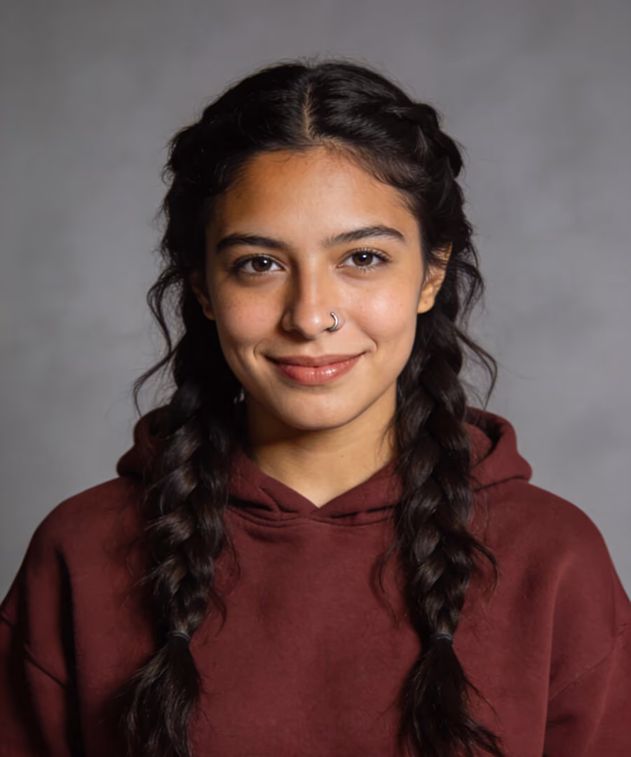 Smiling woman with braided hair wearing a maroon hoodie and a nose ring against a gray background.
