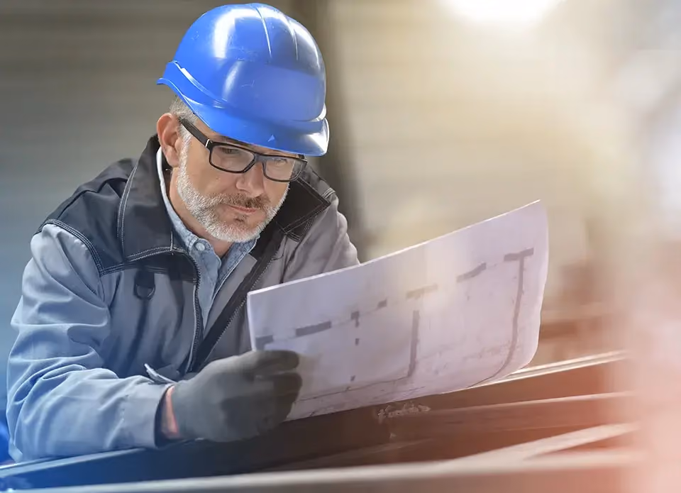 Technicien d'exploitation en casque bleu lisant un plan technique
