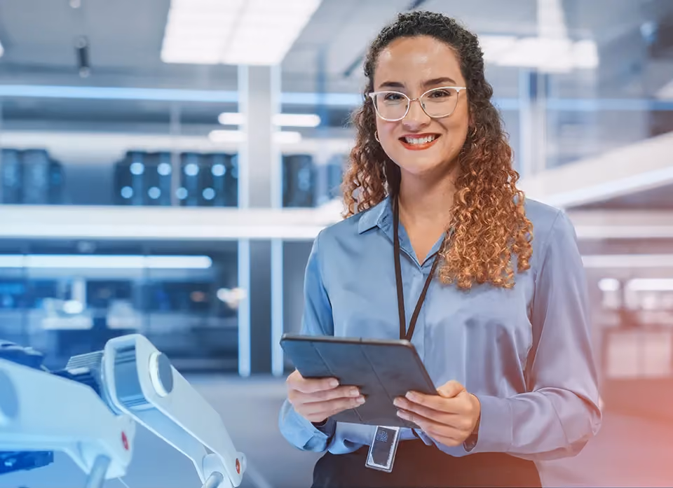 Jeune femme avec badge et tablette dans un couloir technique