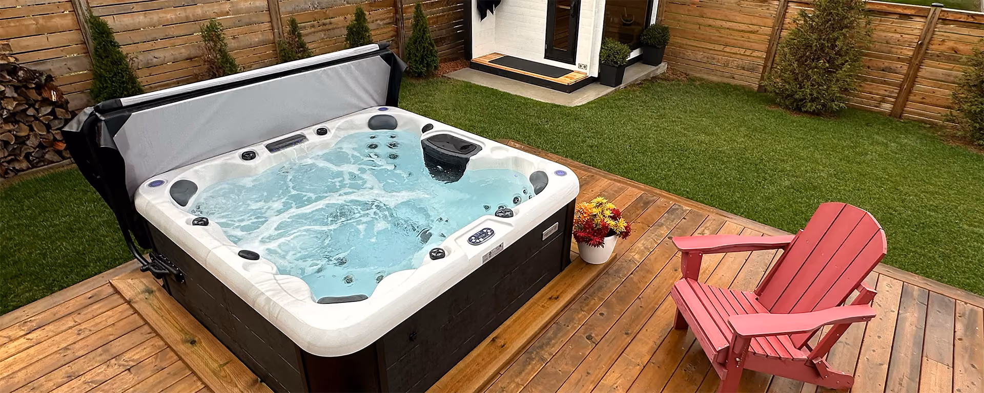 Outdoor hot tub with bubbling water on wooden deck next to a pink Adirondack chair and flowers.