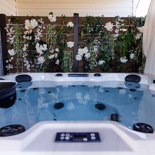 Indoor hot tub with water jets and headrests, floral wall decoration in background.
