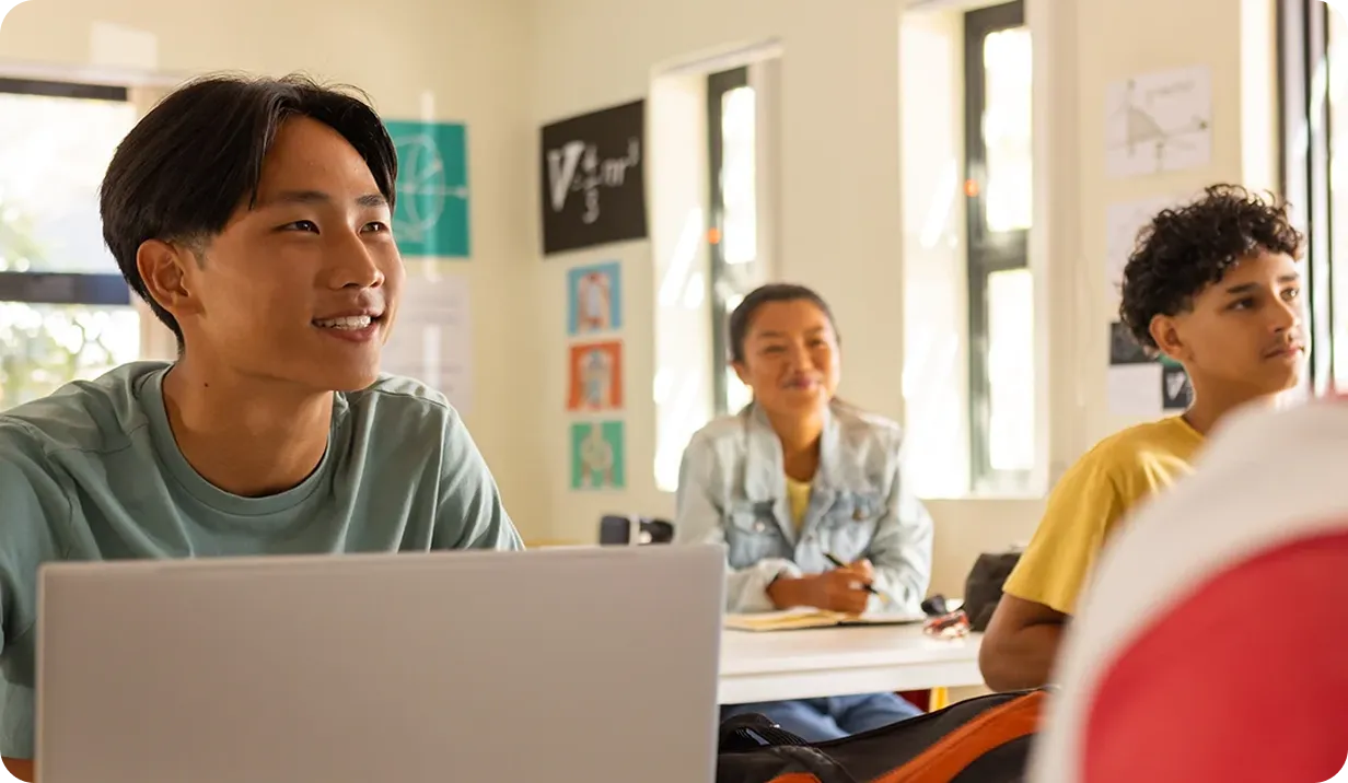 Students working on laptops in a bright classroom