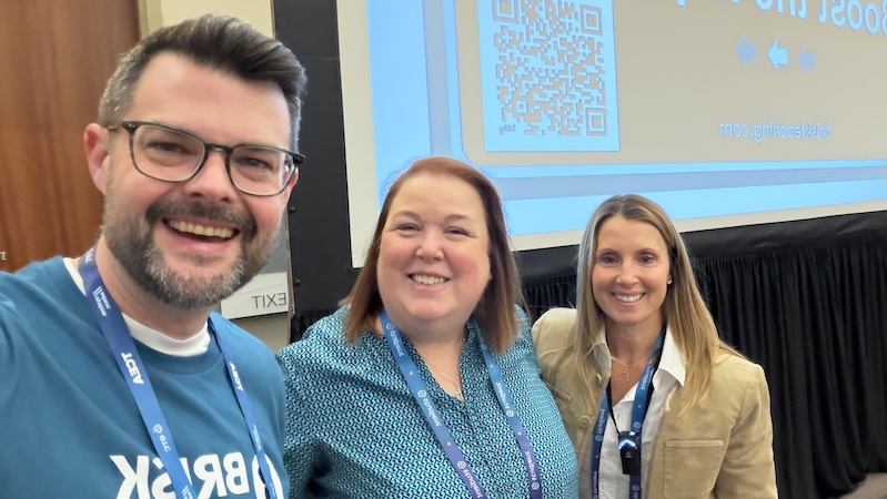 Three Brisk team members smiling during a conference presentation
