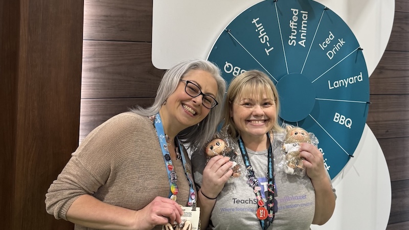 Two educators holding prizes at the Brisk Teaching conference booth