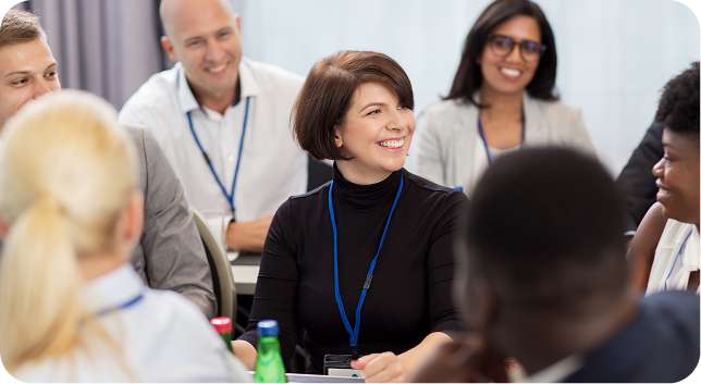 Diverse group of adults smiling and engaged in a discussion at a meeting or workshop.