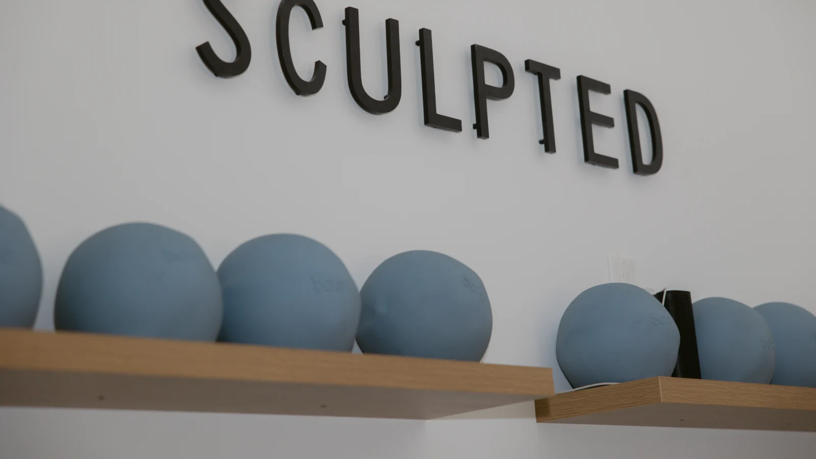 The Sculpted wordmark above a shelf of weighted pilates balls