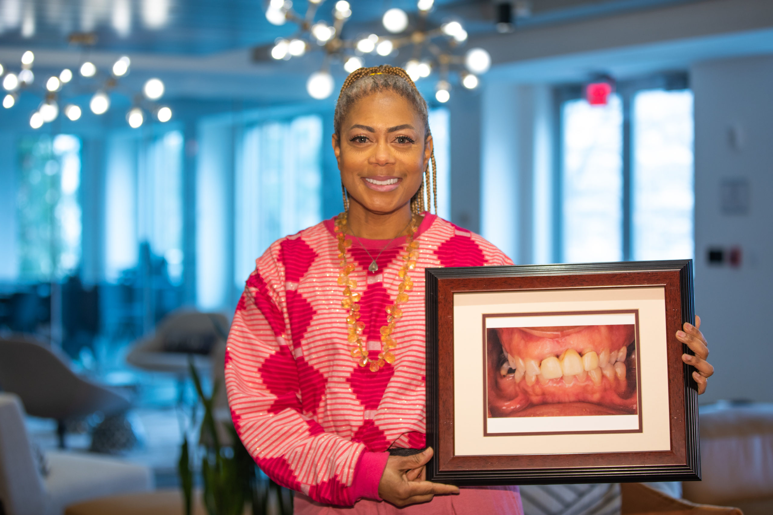 Melanie holding a photograph of her smile before treatment