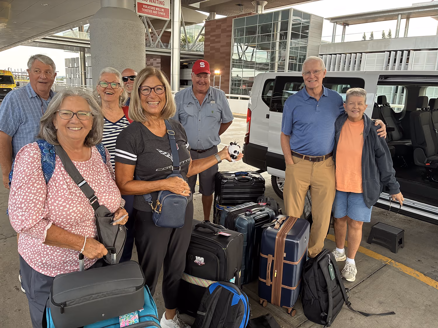 Group of smiling JustU Shuttle passengers after being dropped off at the airport