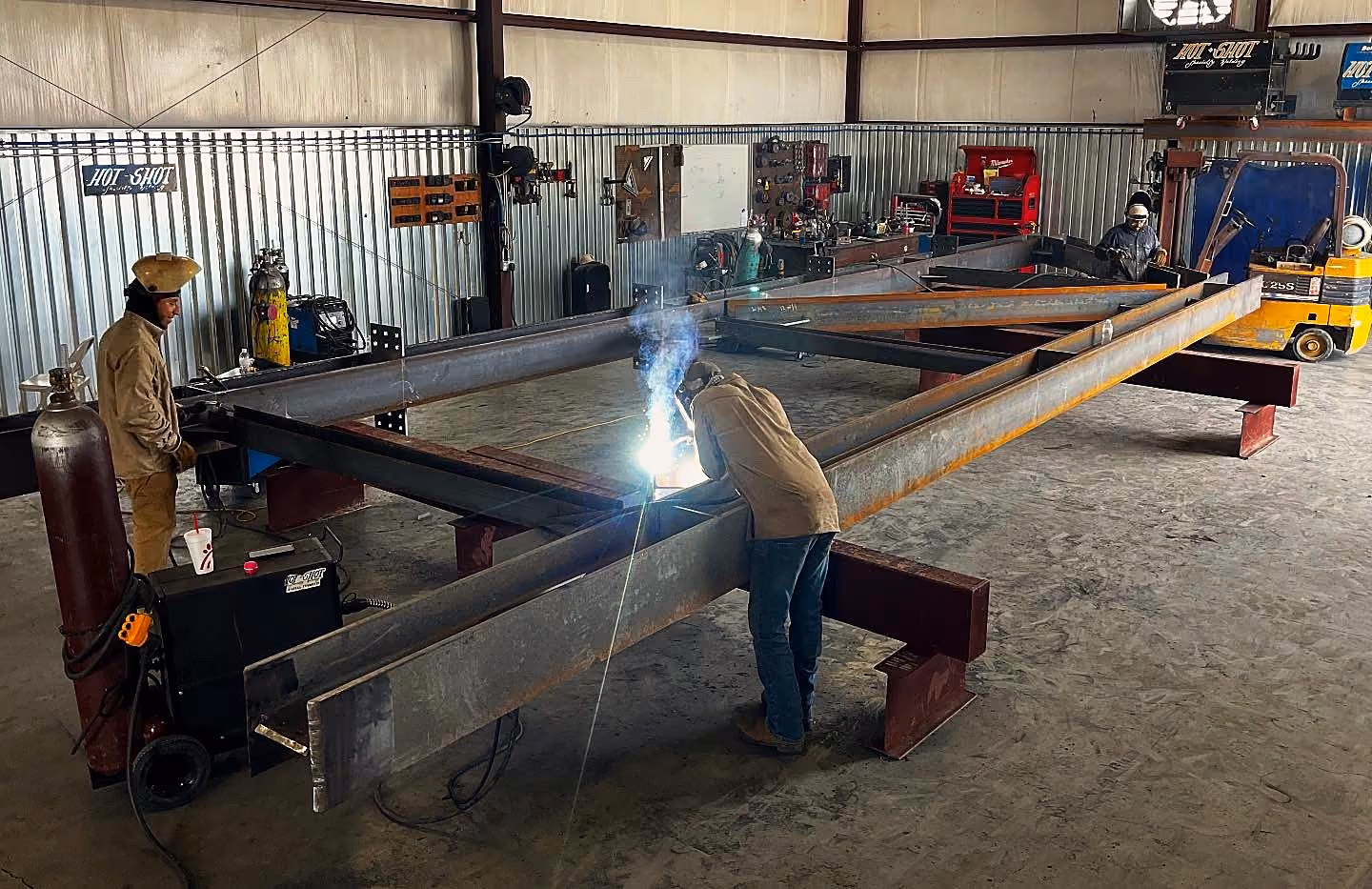 Welder joining a structural steel beam in the Hot Shot fabrication shop