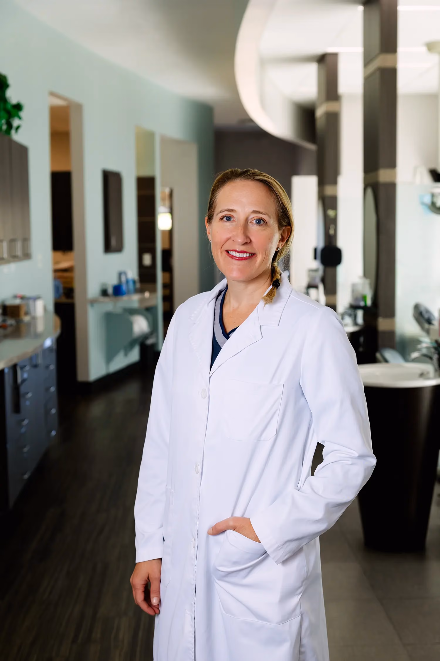 Smiling female doctor in a white coat standing in a modern medical office.