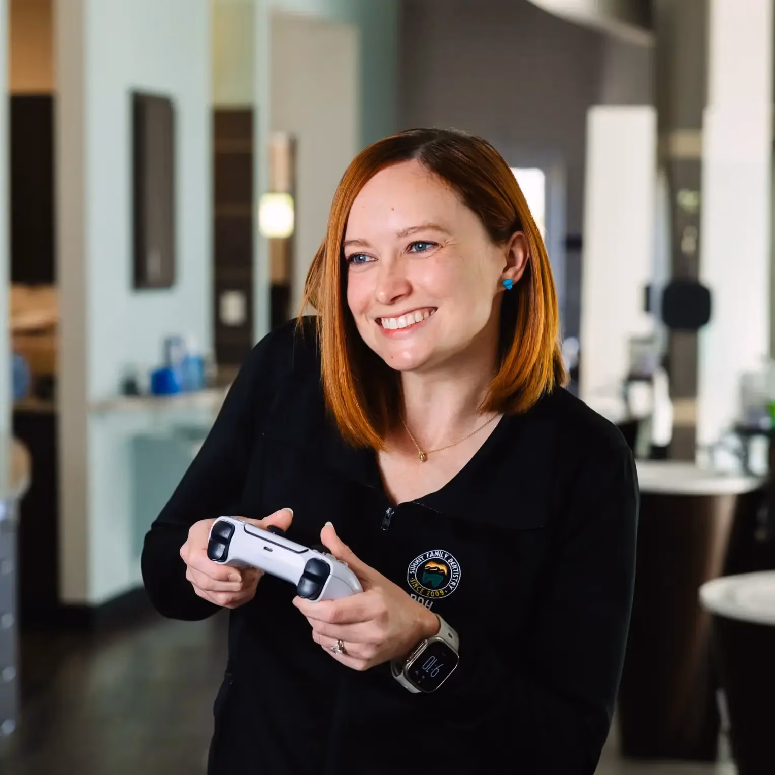 Smiling woman with red hair holding a white video game controller indoors.