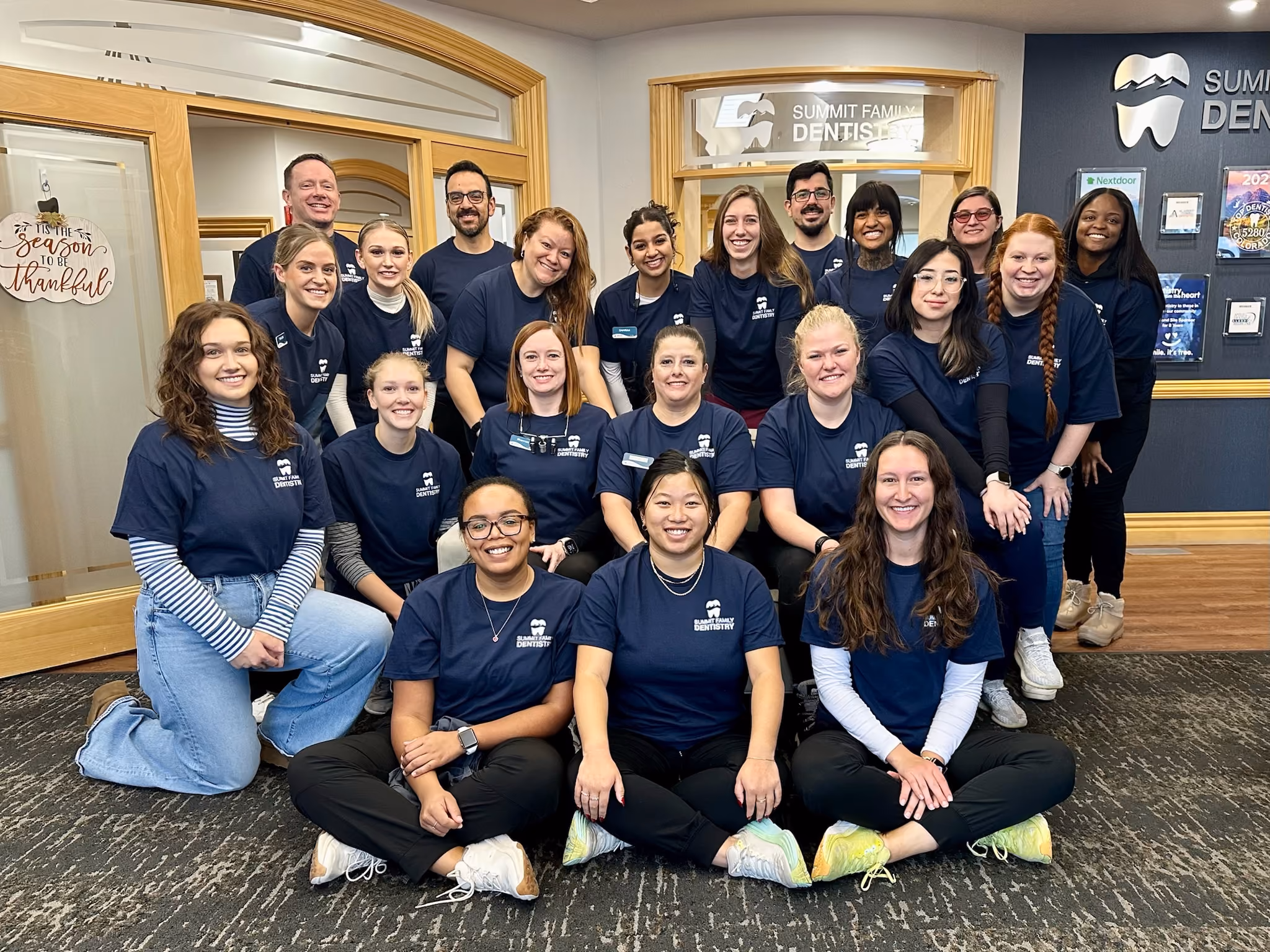 Group photo of smiling Summit Family Dentistry staff in navy blue shirts inside the office.