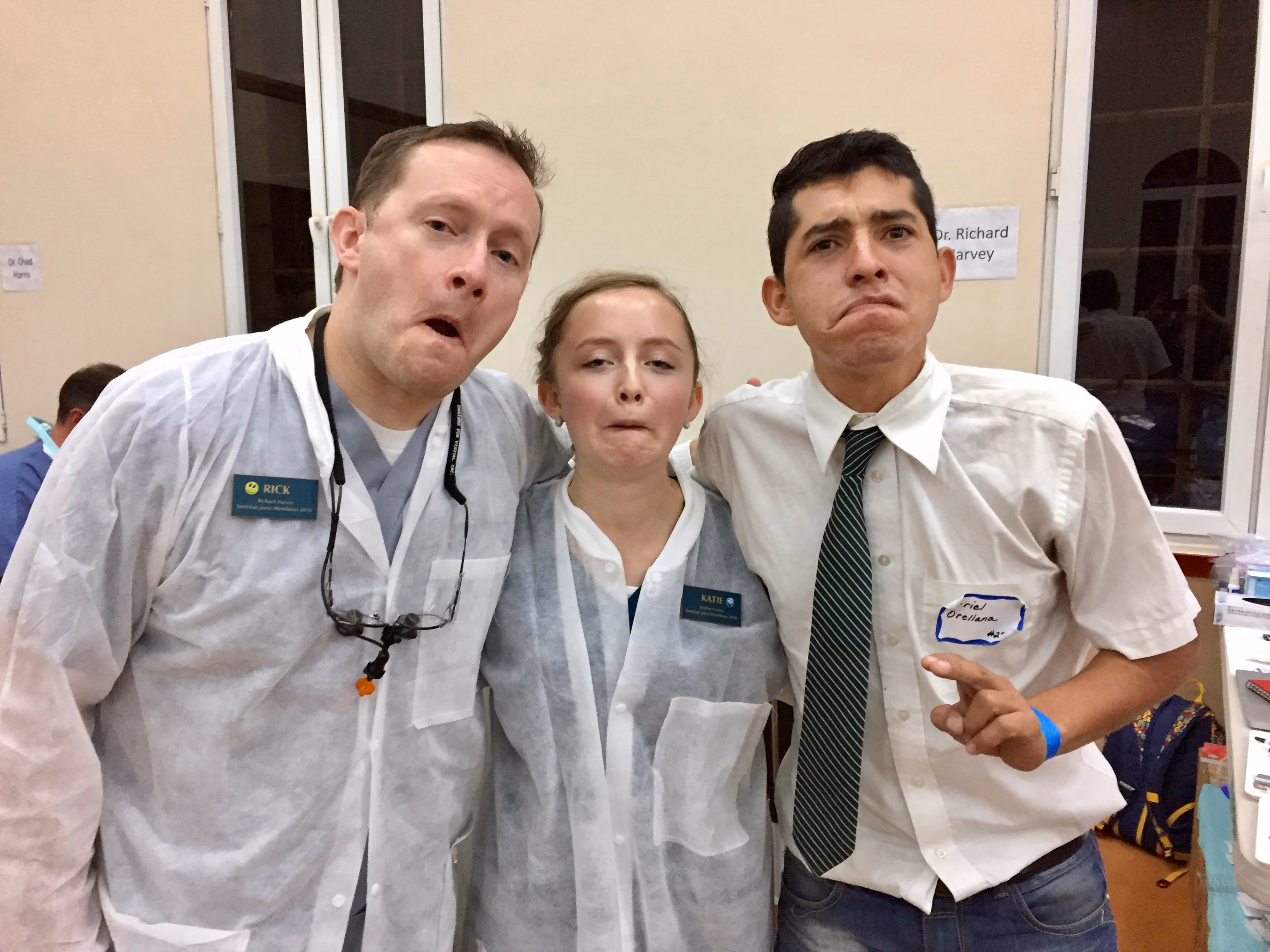 Three people making exaggerated funny faces, with two wearing white lab coats and name tags.