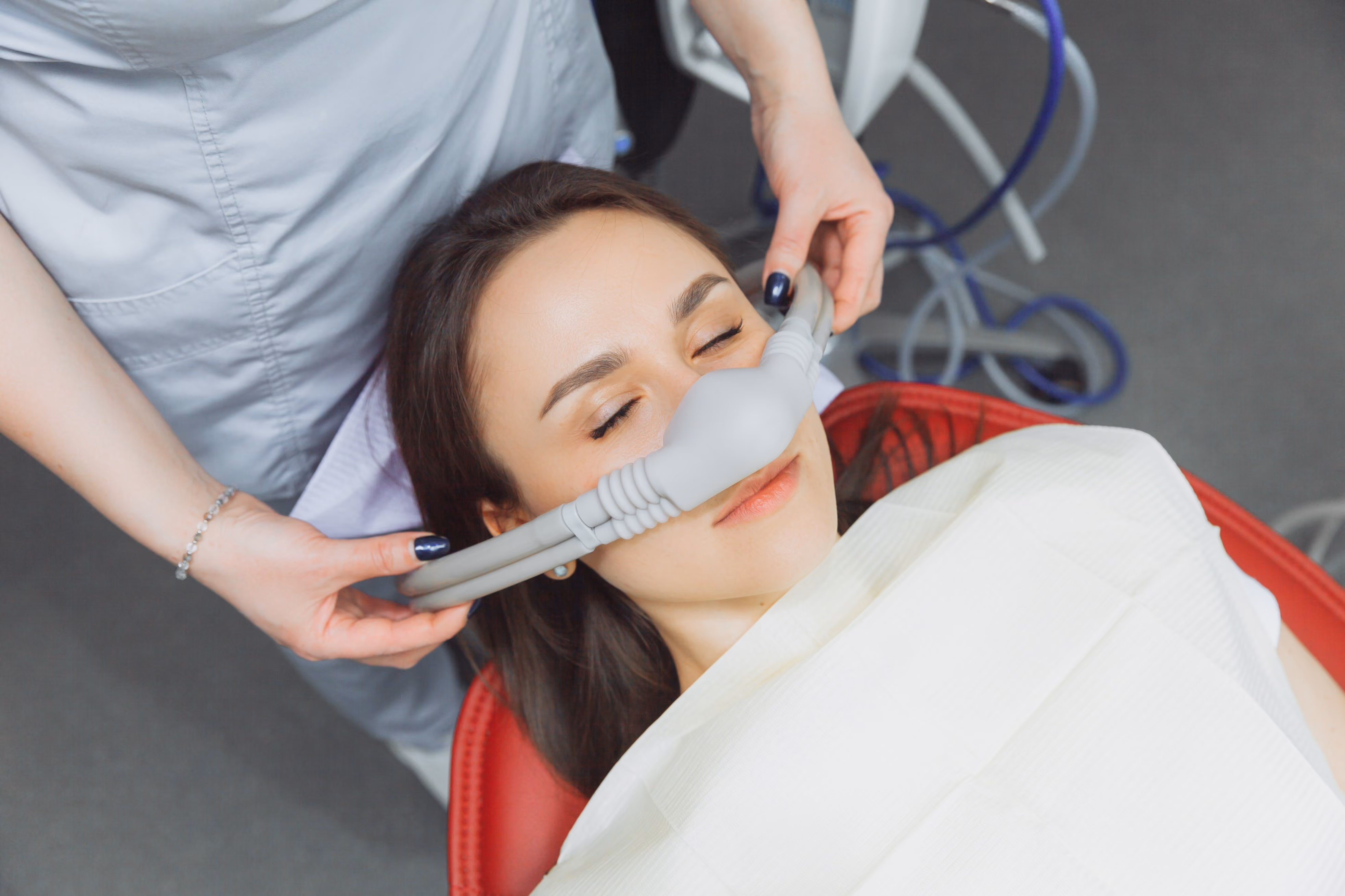Woman reclined with a breathing mask placed over her nose during a dental or medical treatment.